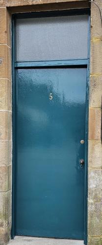a blue garage door in a brick building at Glebe Apartment in Campbeltown