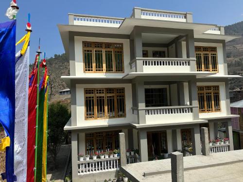 a large white building with flags in front of it at Yangsel Homestay in Dirang Dzong