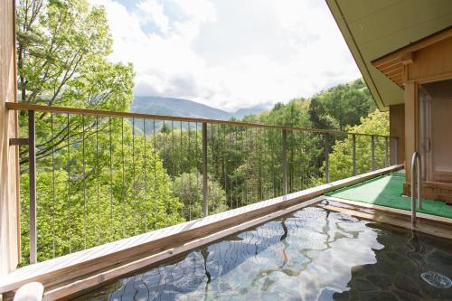 a balcony with a pool with a view of the mountains at Izumigo AMBIENT Azumino Hotel in Azumino