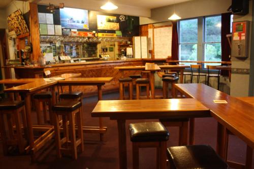 a bar with wooden tables and chairs in a restaurant at Owen River Tavern & Motels in Owen River