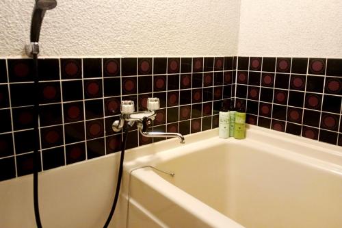 a bath tub in a bathroom with black tiles at Ryokan Wataya in Karatsu