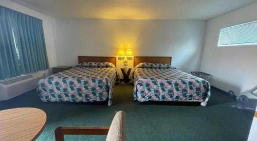 a hotel room with two beds and a table at OYO Riverside Inn John Day OR in John Day