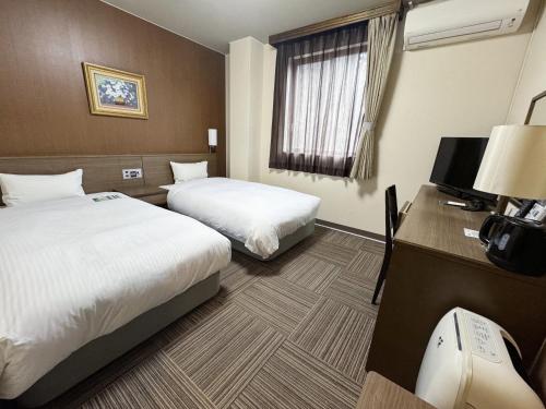 a hotel room with two beds and a desk with a computer at Hotel Route-Inn Court Karuizawa in Miyota
