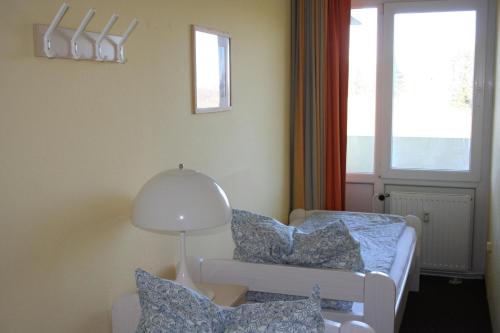 ein Zimmer mit einem Bett und einer Lampe und einem Fenster in der Unterkunft Ferienappartement E226 für 2-4 Personen an der Ostsee in Brasilien