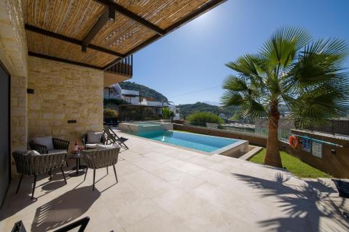 a patio with a table and chairs and a swimming pool at Almi-Cove Hilltop Villas in Almirida