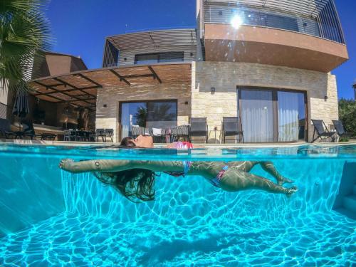 a woman laying in a swimming pool in front of a house at Almi-Cove Hilltop Villas in Almirida