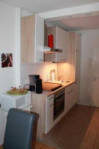 a kitchen with white cabinets and a blue chair at Ferienwohnung L354 für 2-5 Personen an der Ostsee in Schönberg in Holstein