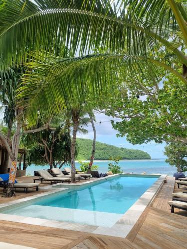 a swimming pool with chaise lounge chairs and the ocean at Mantaray Island Resort in Nanuya Balavu Island