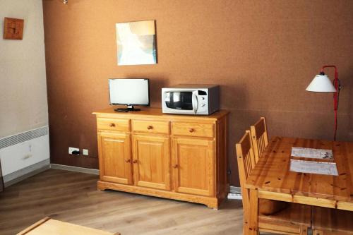 un four micro-ondes installé au-dessus d'une armoire en bois avec une table dans l'établissement Résidence Orr Des Cimes - Orrianes des Cimes 412 MAE-3804, à Le Mélézet