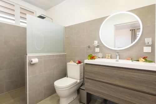 a bathroom with a toilet and a sink and a mirror at Villa Hana in Maharepa