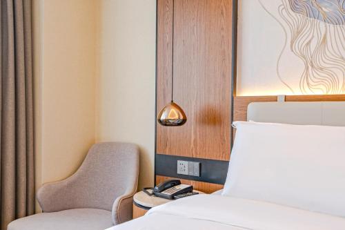 a room with a bed and a chair and a lamp at Yunfei Hotel - Shanghai Hongqiao Wuzhong Road Branch in Shanghai
