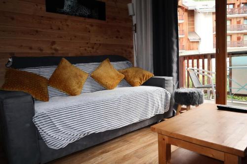 un canapé avec des coussins dessus dans un salon dans l'établissement Les Chalets De Bois Mean - A223 LES BALCONS DE BOIS MEAN : Résidence de standing MAE-0434, aux Orres