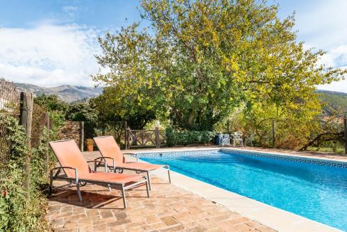 ein Pool mit zwei Stühlen neben einem Baum in der Unterkunft Slow House sa mayma in Nigüelas