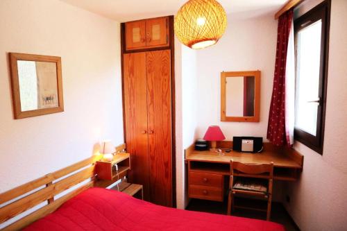 une chambre avec un lit et un bureau avec un couvre-lit rouge dans l'établissement Résidence Le Cairn - CENTRE STATION APPARTEMENT 307 CAIRN MAE-6301, aux Orres