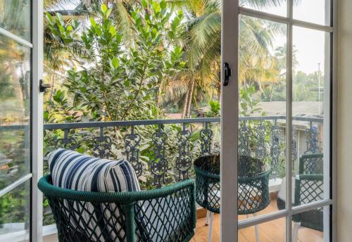 a balcony with a view of a palm tree at Goan Bliss in Varca