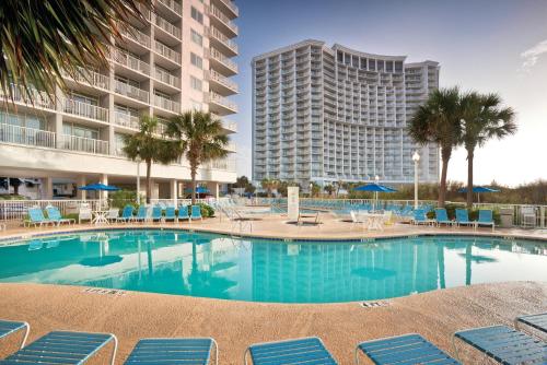 Una piscina con sillas y un gran edificio. en Club Wyndham SeaWatch Resort, en Myrtle Beach
