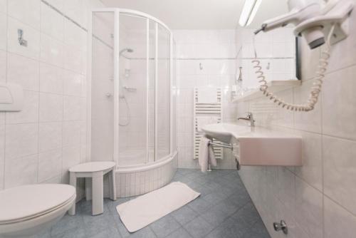 a white bathroom with a sink and a tub and a toilet at Gasthof Hensle in Sankt Gallen