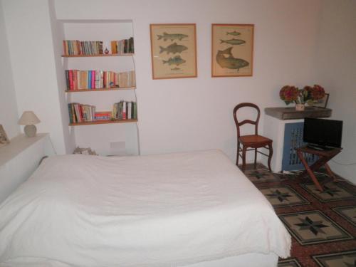 - une chambre avec un lit blanc et une chaise dans l'établissement Maison de l'étang de Thau, à Bouzigues