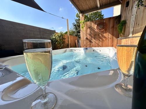 - deux verres de champagne sur une table et un bain à remous dans l'établissement L échappée Rémoise, jacuzzi proche caves champagne, à Reims