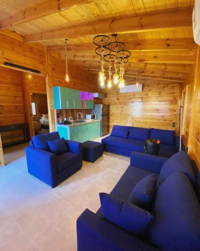 a living room with blue couches and a kitchen at أكواخ البرنسيسة in Jeddah