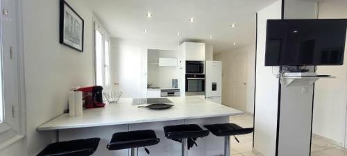 une cuisine avec un comptoir avec des tabourets et une télévision dans l'établissement Le Ferrié - 3 Chambres - Parking Gratuit - proche centre ville, à Grenoble