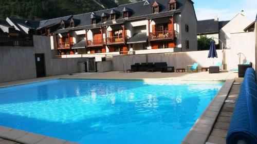 une grande piscine bleue devant un immeuble dans l'établissement Location Logement T3 à Vignec dans les Pyrénées, à Vignec