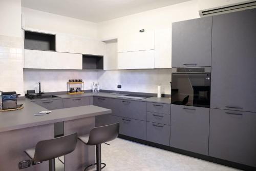 a kitchen with white cabinets and a counter and chairs at Stay&Go - Bilocale con Giardino in Pregnana Milanese