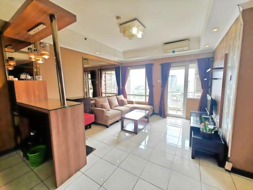 a living room with a couch and a table at Strategic 3BR Sudirman Park Apt with Wi-Fi, Pool,Gym by 2ndHome in Jakarta