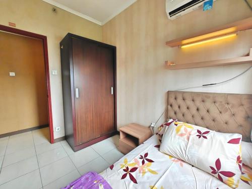 a bedroom with a bed and a wooden door at Strategic 3BR Sudirman Park Apt with Wi-Fi, Pool,Gym by 2ndHome in Jakarta