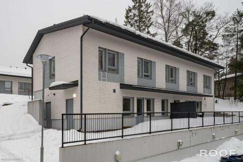 a white house with a fence in the snow at Huoneisto terassilla & parkkipaikalla in Espoo