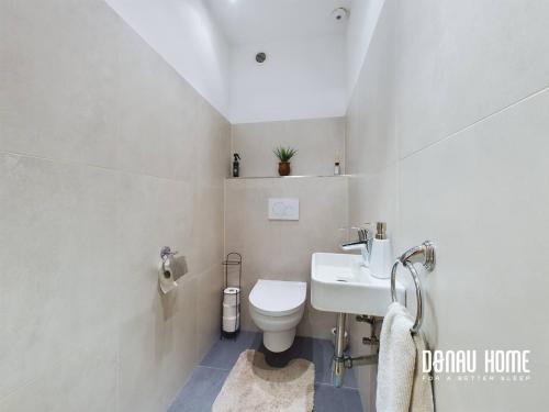 a white bathroom with a toilet and a sink at Idyllisches Ferienhaus Parndorf in Parndorf