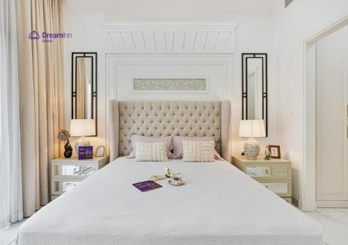 a white bedroom with a large white bed with two lamps at Dream Inn - Modern 1BR in Arjan in Dubai