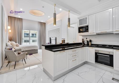 a kitchen with white cabinets and a living room at Dream Inn - Modern 1BR in Arjan in Dubai