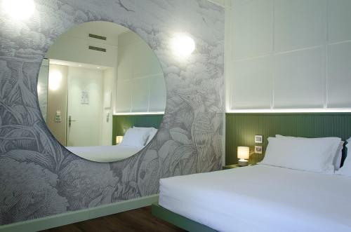 sypialnia z łóżkiem i lustrem w obiekcie Hotel Tiziano - Gruppo Mini Hotel w Mediolanie