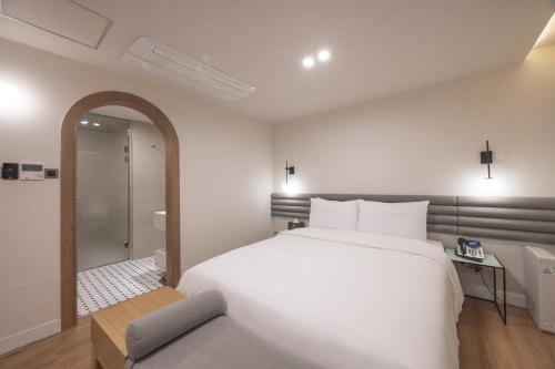 a bedroom with a large white bed and a shower at H-Avenue Hotel Haeundae in Busan