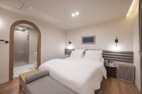 a bedroom with a large white bed and a chair at H-Avenue Hotel Haeundae in Busan