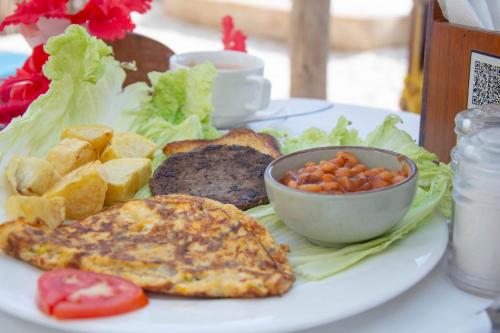 a plate of food with meat and vegetables and a bowl of beans at Equalia Rose Hotel in Jambiani