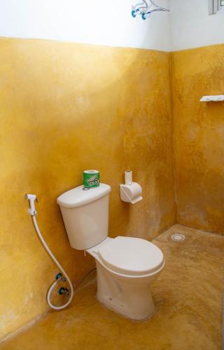 a bathroom with a white toilet in a yellow wall at Equalia Rose Hotel in Jambiani