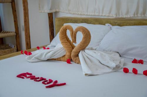 two towelcovered swans on a bed with red hearts at Equalia Rose Hotel in Jambiani