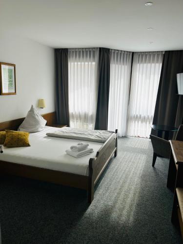a hotel room with a bed and a chair at Landhotel Sonnenbühl in Sonnenbühl