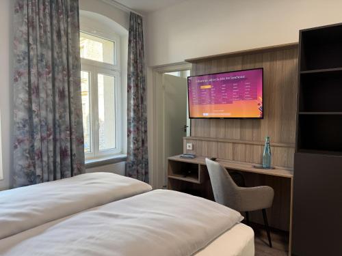a hotel room with a bed and a tv on the wall at Hey! Halle - Dein Stadthotel in Halle an der Saale