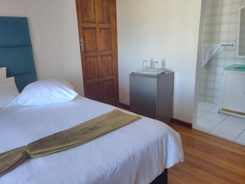 a bedroom with a white bed and a wooden door at MayBach Hills Palace Guesthouse in Saldanha