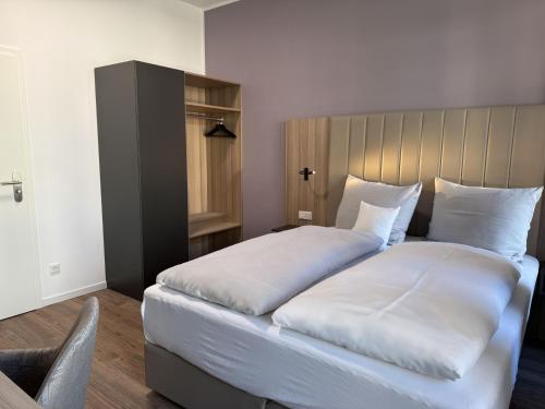 a bedroom with a large bed with white sheets at Hey! Halle - Dein Stadthotel in Halle an der Saale