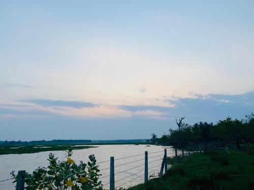 a view of a river with a fence next to it at Lago Inn in Tissamaharama