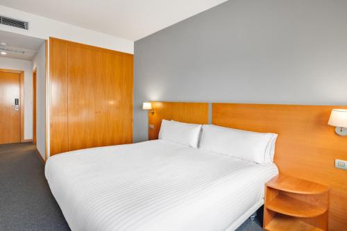 a bedroom with a white bed and a wooden headboard at B&B HOTEL Barcelona Mollet Porta de Gallecs in Mollet del Vallès