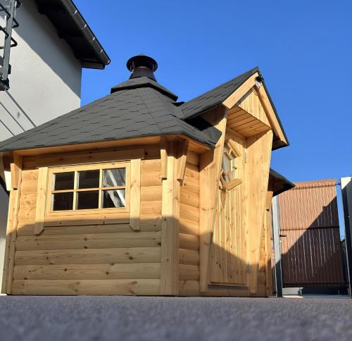 une cabane en bois avec un toit noir dans l'établissement Le Chalet - Changer d'air en Moselle, à Longeville-lès-Saint-Avold