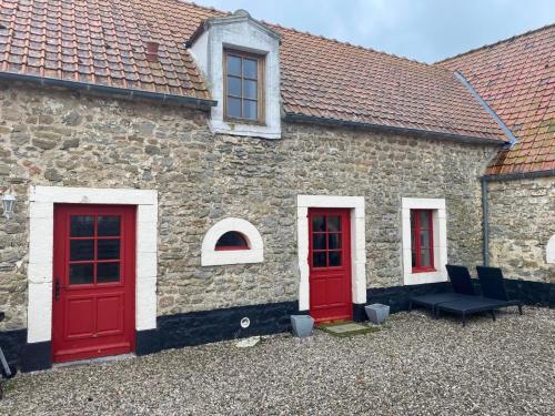 a stone building with red doors and chairs in front at Gîte du Chatelet in Tardinghen