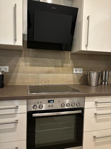 a kitchen with a stove and a microwave at Wood&Stone - Modernes Haus in Seenähe am Tankumsee mit Terrasse, Outdoorküche, Kamin, Homeoffice Bereich & voll ausgestatteter Küche im Naherholungsgebiet in Isenbüttel