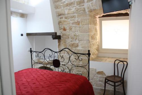 sypialnia z czerwonym łóżkiem i kamienną ścianą w obiekcie Lilla B&B w mieście Molfetta