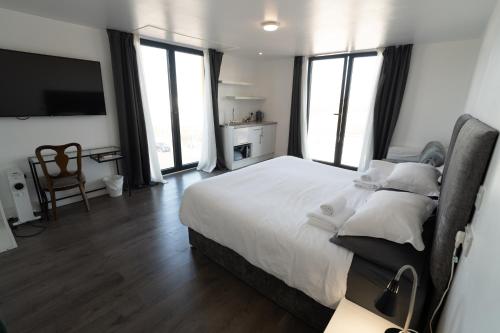 a bedroom with a large white bed with windows at Abbey Point Hotel in London